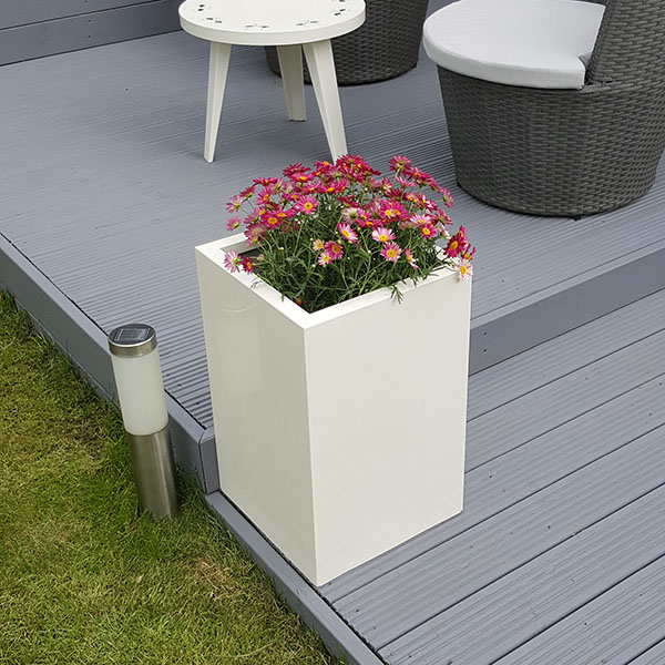 Off-White Tall Flower Planter on grey garden decking with seating in the background.