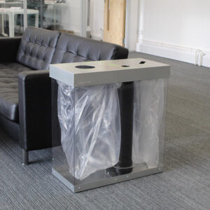 Box Cycle Cup Recycling Bin in silver next to an office couch.